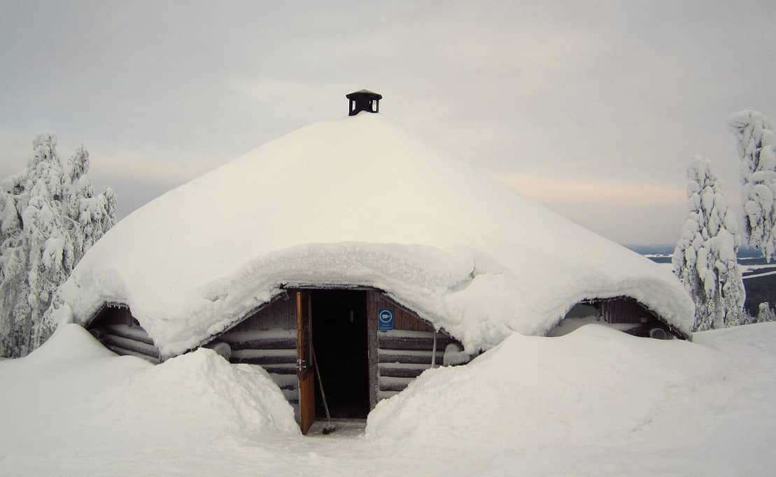 cabin with lots of snow on the roof